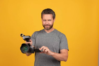 Gülümseyen sakallı adam videograf kamera ve görüntü yönetmeni ile vlog için film yapıyor.