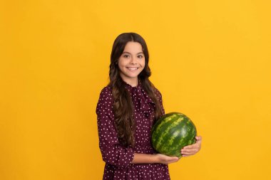 Mutlu çocuk karpuz tutuyor. Sarı arka planda karpuz. Meyveli çocuk.