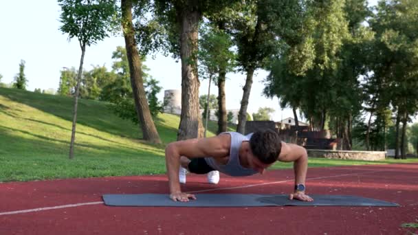 Δυνατός άντρας κάνει κάμψεις με παλαμάκια στο στρώμα γυμναστικής στο πάρκο, αθλητισμός — Αρχείο Βίντεο