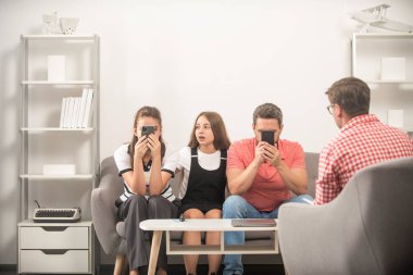 Aile terapisi. Çocuklu aileler sosyal hizmetlilerle konuşur. Telefon bağımlısı anne-baba-kız