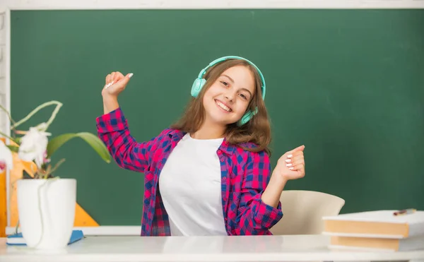 Χαρούμενο παιδί ακούει μουσική σε ακουστικά στον πίνακα, αξεσουάρ ήχου — Φωτογραφία Αρχείου
