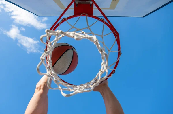 Pelota de baloncesto volando a través de canasta en manos de jugadores, ganando — Foto de Stock