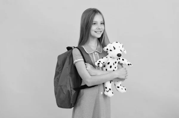 Okul çantası, oyuncak köpeği ve çocukluğu olan mutlu bir kız çocuğu. — Stok fotoğraf