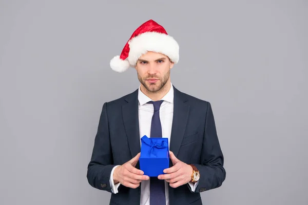 Biznesmen facet nosić Santa kapelusz trzymając pudełko na szarym tle, zakup — Zdjęcie stockowe