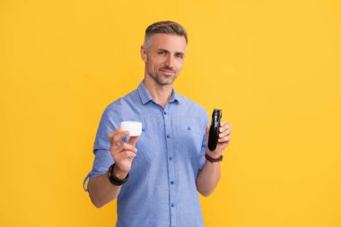 Berber dükkanı. traş sonrası. Adam elektrikli tıraş makinesi ve krem tutuyor. Gri saçlı adam elektrikli jilet sunuyor.