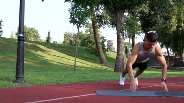 Hombre musculoso haciendo flexiones con aplausos en la alfombra de fitness al aire libre, poder — Vídeos de Stock