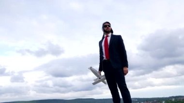 Pilot şapkalı ve gözlüklü başarılı bir adam. Arka planda uçak, iş başarısı.