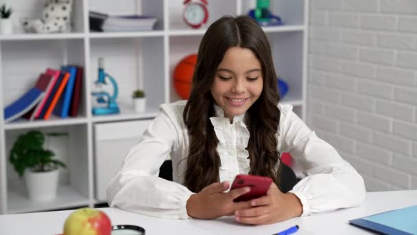 Vrolijk kind in uniform en krullend haar wijzerplaat nummer en praten over de telefoon in de klas, communicatie. — Stockvideo