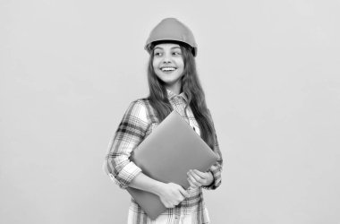 Kasklı genç kız dizüstü bilgisayar kullanıyor. İnşaatçı çocuk bilgisayarı tut. Bina ve inşaat. webinar.