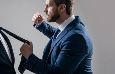 Saldırgan menajer, erkek meslektaşını yumrukladı. Kravatı gri arka plan, saldırganlık..