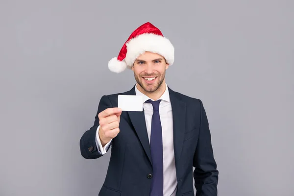 Szczęśliwy biznesmen facet nosić Santa kapelusz trzymać karty debetowej na szarym tle, przestrzeń do kopiowania, członkostwo. — Zdjęcie stockowe