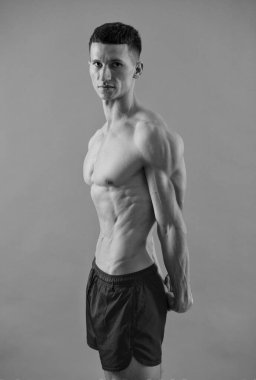 Göbek, göğüs ve pazılara sahip kaslı bir adam spor şortuyla poz veriyor, vücut geliştirici.