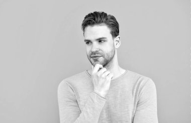 Tıraşsız yüzü olan yakışıklı bir adam. Gri arkaplan, ciddi.