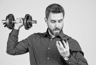 Güçlü sakallı iş adamının halterle eğitilmesine ve akıllı telefona bakmasına şaşırdım.