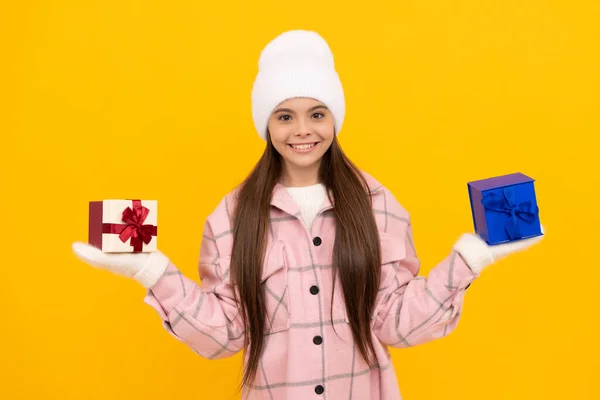 Criança feliz no chapéu e mitenes escolher caixa de presente no fundo amarelo, escolha — Fotografia de Stock