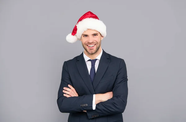 Szczęśliwy biznesmen w kapeluszu Mikołaja na szarym tle, Boże Narodzenie — Zdjęcie stockowe