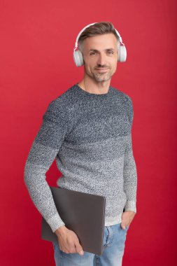 İşine gelince internetten öğreniyorsun. Mutlu adam dizüstü bilgisayar tutuyor. Çevrimiçi ses kursları dinleniyor