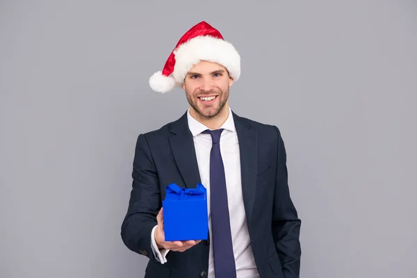 Щасливий чоловік у діловому костюмі і капелюх Санти Клауса тримають подарункову коробку, привітання — стокове фото