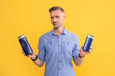 Adam şampuan şişesini ya da saç kremini seçiyor. Günlük alışkanlıklar ve kişisel bakım.