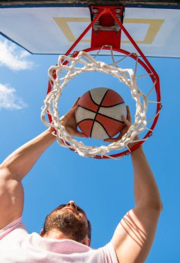 Adam basketbol topunu elleriyle ağ halkasına sokuyor, başarı.