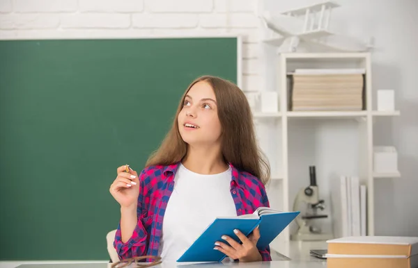 Tiener meisje in de middelbare school het maken van notities werkboek op schoolbord, wijsheid — Stockfoto