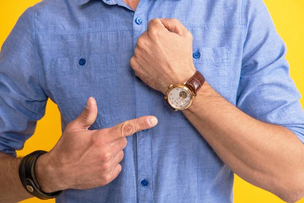 Gestutzter Mann zeigt mit dem Finger auf Handuhr auf gelbem Hintergrund, Zeit — Stockfoto