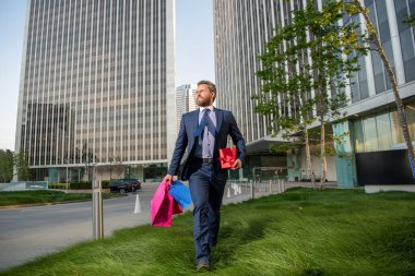Hediyeli kutusu olan yakışıklı bir adam. Girişimci doğum günü hediyesi taşır. Erkekler alışveriş torbalarını tutar..