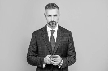 Takım elbiseli kendine güvenen işadamı telefonda mesaj yazıyor, blog yazıyor.