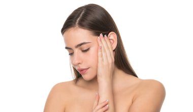 pürüzsüz ve yumuşak kadın teni. Kadın pürüzsüz yüze dokunur. Çıplak omuzlu genç kız..