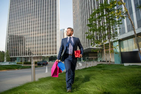 Hediyeli kutusu olan yakışıklı bir adam. Girişimci doğum günü hediyesi taşır. Erkekler alışveriş torbalarını tutar..