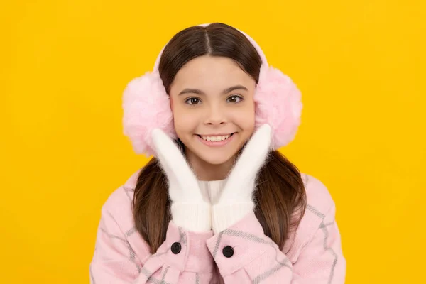 Criança feliz em mitenes de inverno e auriculares em fundo amarelo, inverno — Fotografia de Stock