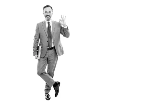 Щасливий бізнесмен у костюмі повної довжини тримає комп'ютер ізольовано на білому просторі копіювання, гаразд — стокове фото