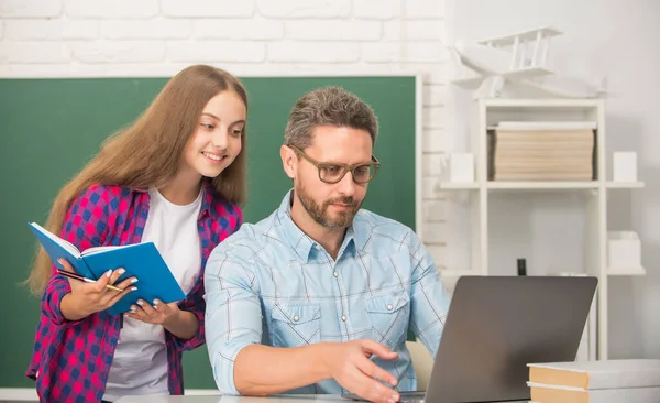 Geschäftiges Vater-Kind-Lernen in der Schule mit Buch und Laptop auf Tafel-Hintergrund, Elternschaft — Stockfoto