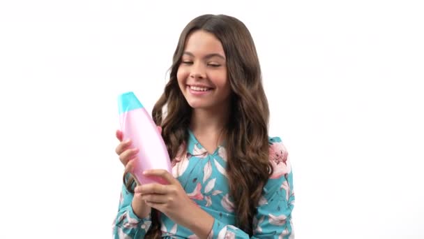 Cheerful kid girl with curly hair offer to wash hair with teen shampoo product, presenting product — Stock Video