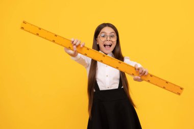 Okul üniformalı ve gözlüklü genç kız matematik cetvelini ölçmek ve trigonometri için tutuyor.