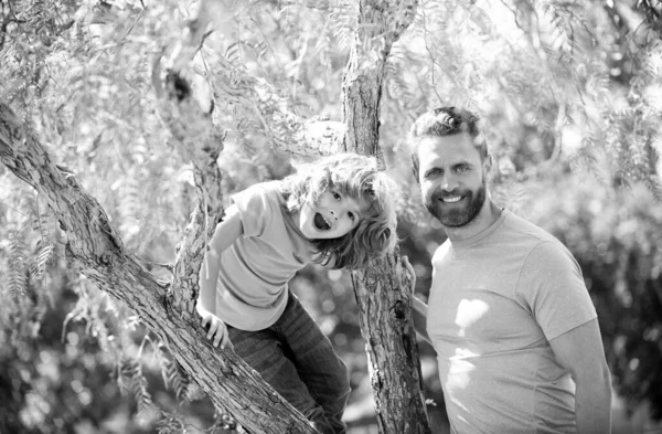 Šťastná rodina. Otec a syn se usmívají na stromě. Rodinná zábava. Dětství a rodičovství — Stock fotografie