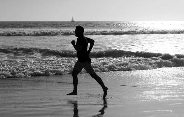 Yaz plajında deniz suyu ve güneşle koşan atletik adam silueti, motivasyon
