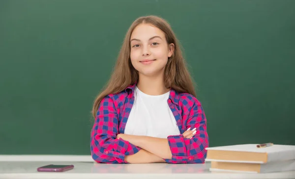 Wesoły dzieciak siedzi w klasie na tablicy, wrzesień — Zdjęcie stockowe