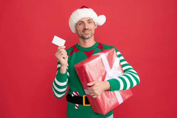 Hombre feliz con tarjeta de débito para ir de compras. hombre en traje de elfo y sombrero de Santa Claus. —  Fotos de Stock