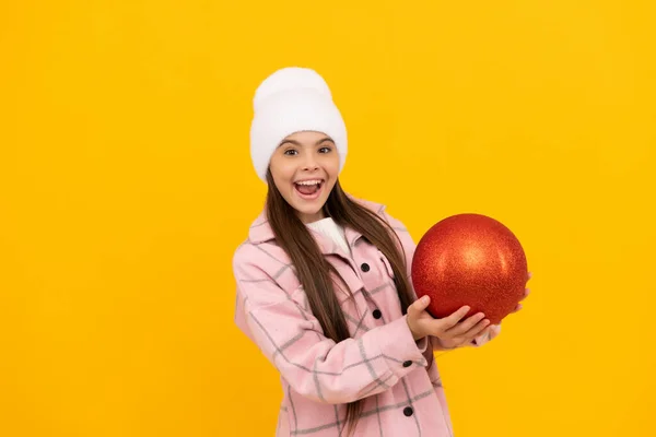 Menina adolescente com bola decorativa vermelha no fundo amarelo. xmas decoração de férias. — Fotografia de Stock