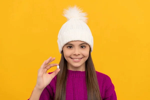 Υγιεινό τρόπο ζωής. Παιδική υγεία. χαρούμενο παιδί με χειμερινό καπέλο με χάπι. συμπλήρωμα διατροφής. — Φωτογραφία Αρχείου
