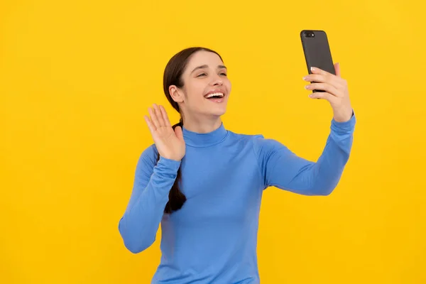 Felice ragazza gesticolando ciao su smartphone mentre la videochiamata, vlog — Foto Stock