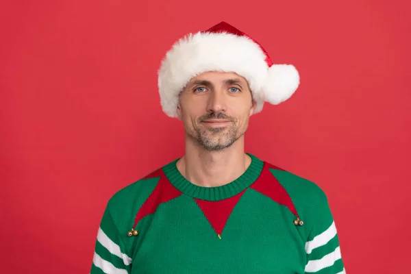 Щаслива людина в ельфійському костюмі. Різдвяний хлопець у капелюсі Санта-Клауса на червоному тлі. щасливий новий рік . — стокове фото