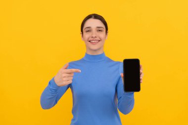 Akıllı telefonu işaret eden gülümseyen bayan, buraya bak.