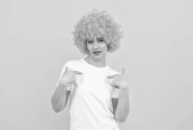 Kıvırcık palyaço peruğu takmış kendine güvenen, kendini beğenmiş, kendini beğenmiş bir kadın.