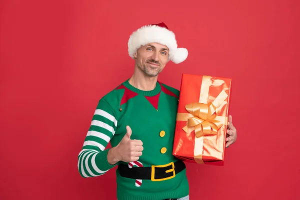 Feliz regalo de Navidad. Pulgar hacia arriba. hombre feliz en traje de elfo y sombrero de Santa Claus. — Foto de Stock