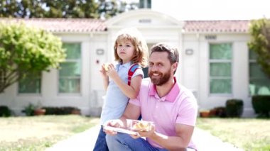 Neşeli baba ve çocuk okul dışında kahvaltı yapıyor. Ağır çekimde, birinci sınıfta.