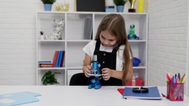 Biyoloji dersi ve eğitim için mikroskop kullanmakla meşgul bir öğrenci.