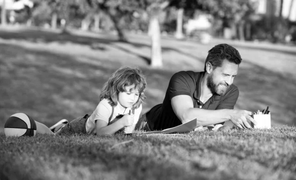 Pai e filho relaxar na grama no parque aprender a desenhar, tutoria — Fotografia de Stock