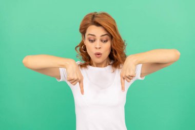 Kıvırcık saçlı, parmaklarını aşağı gösteren şaşırmış bir kadın. Şuraya bak. Kadın model..